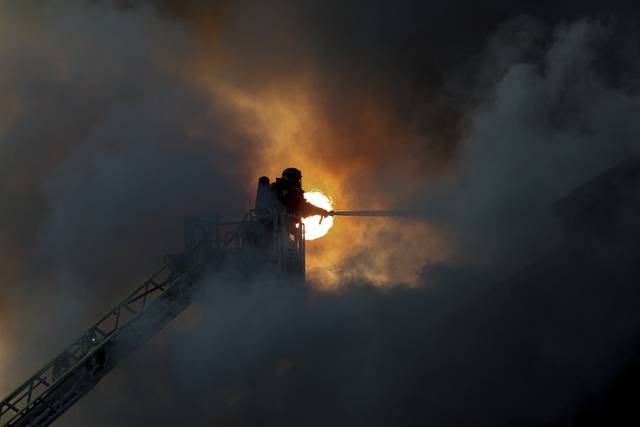14일 러시아군의 드론 공격을 받은 우크라이나 자포리자의 피해지역에서 한 구조대원이 화재를 진압하고 있다. AP 연합뉴스