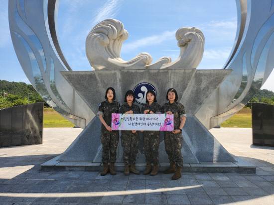 지난 11일 모발기부 장병들이 39사단 상징탑 앞에서 모발기부 관련 플래카드를 들고 기념촬영을 하고 있다. 사진 맨왼쪽부터 황지희 소령, 김민지 중위, 박한별 중사, 남가영 상사. 사진=39사단