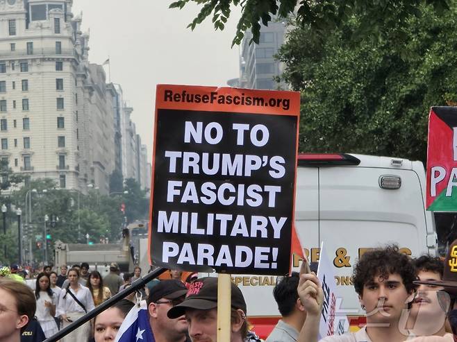 14일(현지시간) 워싱턴DC에서 미 육군 창설 250주년 기념 열병식이 열린 가운데 행사장 주변에서 '트럼프의 파시스트 군사 퍼레이드에 반대한다'는 피켓을 든 시위대가 행진하고 있다. ⓒ News1 류정민 특파원