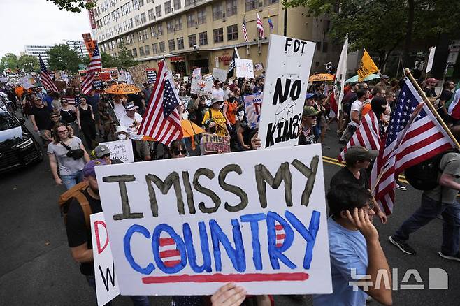 [워싱턴=AP/뉴시스] 미 육군 창설 250주년 기념 군사 퍼레이드와 도널드 트럼프 대통령의 79번째 생일이 겹친 14일(현지 시간) 워싱턴에서 반트럼프 시위대가 손팻말을 들고 행진하고 있다. 미 전역에서 트럼프 대통령의 권위주의적 국정운영을 비판하는 '노 킹스(No Kings)' 시위가 이어지고 있다. 2025.06.15.