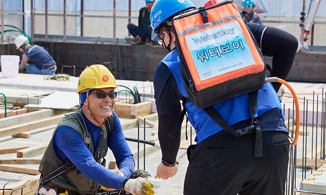 12일 HDC현대산업개발의 한 건설현장에서 근로자 온열질환 예방을 위한 ‘HDC 고드름 캠페인’의 일환으로 작업자에게 식수를 전달하고 있는 모습. HDC현대산업개발 제공
