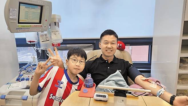 강성만(오른쪽) 유한양행 부장이 15일 서울 은평구 헌혈카페 구파발점에서 생애 181번째 헌혈을 하며 아들 지후군과 브이(V) 자를 그리고 있다. /강성만씨 제공