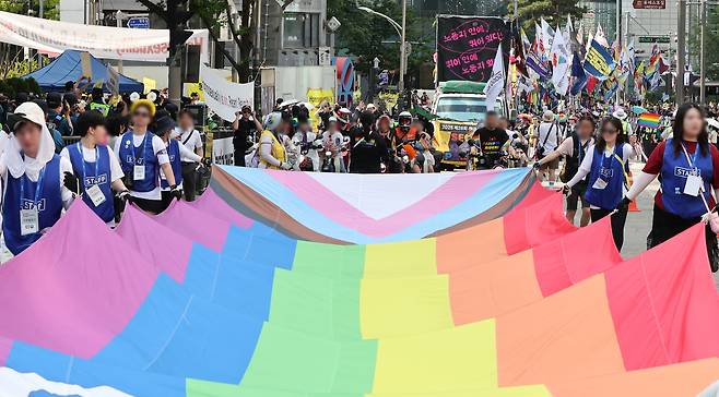 Participants at the Seoul Queer Culture Festival carry a large rainbow flag representing the LGBTQ community near Myeongdong Cathedral in Jung District, central Seoul, on June 14. [NEWS1]