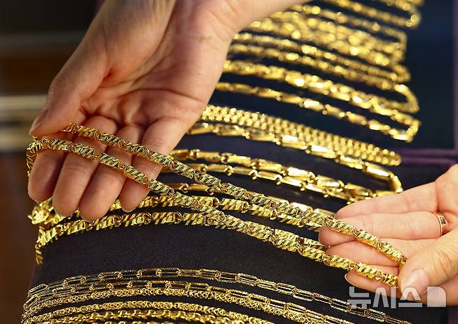 [서울=뉴시스] 김근수 기자 = 15일 서울 종로구 골드팡 종로직영점에서 직원이 금 제품을 들어 보이고 있다. 이스라엘의 이란 핵시설 공습으로 지정학적 리스크가 커지며 금값이 급등했다. 골드만삭스와 뱅크오브아메리카는 중앙은행 금 매입 등을 이유로 금값이 향후 온스당 4,000달러까지 오를 것으로 전망했다. 2025.06.15. ks@newsis.com