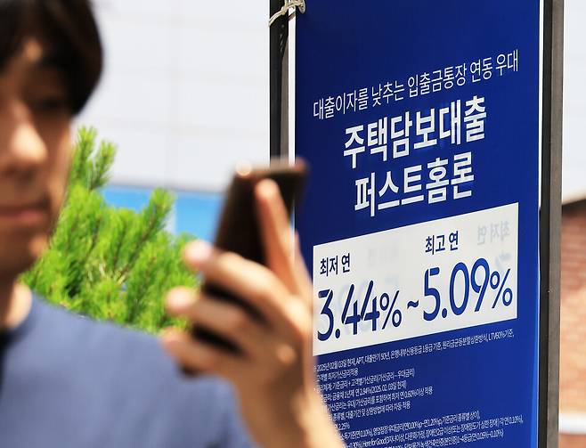 16일 금융권에 따르면, 5대 은행(KB국민·신한·하나·우리·NH농협)의 5월 말 기준 전체 원화대출 연체율 평균값은 0.49%로 집계됐다. 사진은 서울 시내 은행 앞&nbsp;대출&nbsp;홍보물을 지나는 시민의 모습&nbsp;ⓒ연합뉴스