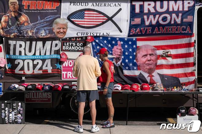 도널드 트럼프 대통령의 지지자들이 스타디움 밖에 전시된 트럼프 기념품과 응원 현수막을 구경하고 있다. 2023.11.8. ⓒ AFP=뉴스1 ⓒ News1 김성식 기자