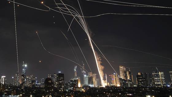 지난 13일(현지시간) 이스라엘 텔아비브 상공에서 이스라엘 아이언돔 방공 시스템이 가동되는 가운데 이란의 미사일 일부가 요격망을 뚫고 건물을 타격하고 있다. AP=연합뉴스