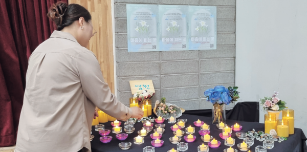 지난 4월25일 올해로 제10회를 맞은 유족을 위한 추모행사 ‘마음에 피는 꽃’에서 한 참여자가 불을 밝히고 있다. 수원시자살예방센터 제공