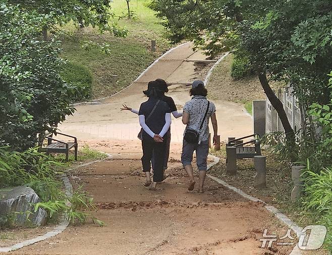 빗물로 일부 구간이 유실된 전북 전주 효열·솔바람공원 맨발길을 이용 중인 시민들. 2025.6.17/신준수 기자