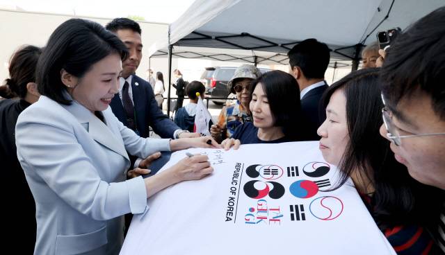 G7 정상회의에 참석하는 이재명 대통령과 함께 캐나다를 방문한 김혜경 여사가 17일(현지시간) 캘거리 한인회관에서 환영나온 주민들의 요청에 티셔츠에 서명하고 있다. 연합뉴스.