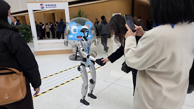 [베이징=뉴시스] 박정규 특파원 = 중국의 첨단기술 포럼인 '2025년 중관춘 포럼 연례회의가 27∼31일 '신품질 생산력과 글로벌 과학기술 협력'을 주제로 개최된다. 28일 오전 포럼 행사장 로비에서 관람객이 휴머노이드 로봇과 악수하고 있다. 2025.03.28