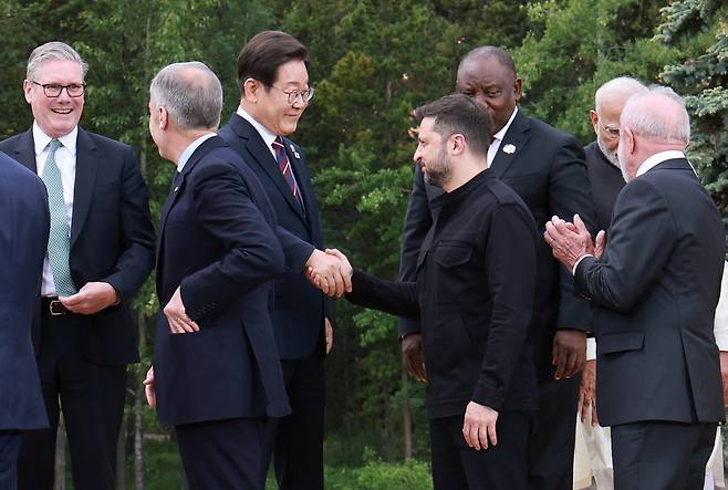 이재명 대통령과 볼로디미르 젤렌스키 우크라이나 대통령이 17일(현지시간) 캐나다 앨버타주 캐내내스키스 주요 7개국(G7) 정상회의장에서 G7 및 초청국 기념촬영 후 악수하고 있다. [연합]