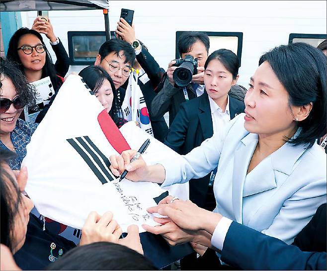 G7 정상회의에 참석하는 이재명 대통령과 함께 캐나다를 방문한 김혜경 여사가 17일(현지시간) 캘거리 한인회관에서 환영나온 주민들의 요청에 태극기에 서명하고 있다.  [연합]