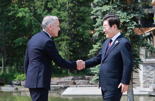 이재명 대통령이 17일(현지시간) 캐나다 앨버타주 캐내내스키스 주요 7개국(G7) 정상회의장에서 열린 초청국 공식 환영식에 도착해 의장국 마크 카니 캐나다 총리와 인사하고 있다. 연합뉴스