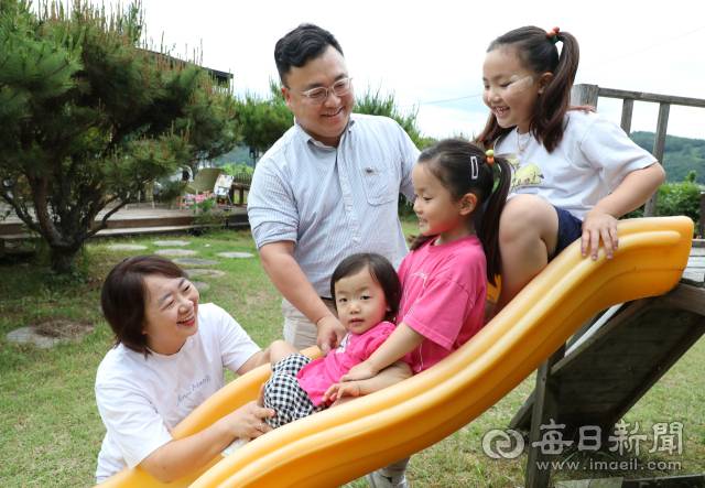 김종명·배정란 씨 부부가 집 마당 미끄럼틀에서 놀고 있는 아이들을 쳐다보며 행복한 미소를 짓고 있다. 정운철 기자 woon@imaeil.com