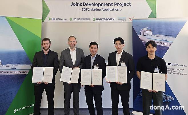 HD현대가 독일 뒤셀도르프 소재 HD유럽연구센터에서 유럽 선급 및 선사와 SOFC 시스템 크루즈선 적용을 위한 기술 공동개발 협약을 체결했다. 염구섭 HD유럽연구센터장 상무(가운데)와 변준영 HD하이드로젠 사업개발팀 책임(오른쪽 두 번째), 김민석 HD한국조선해양 선박연료전지시스템 연구실 책임(오른쪽 첫 번째), 루카스 리트(Luka RITT) DNV 도면승인엔지니어(왼쪽 첫 번째), 크리스티안 레르허(Christian Lerche 투이크루즈 선단운영 및 보건담당 이사 등이 협약을 체결한 후 기념사진을 촬영하고 있다.