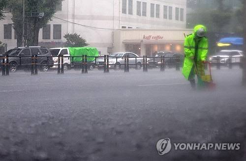 지난 16일 폭우가 쏟아진 서울 서대문구에서 환경미화원이 인도를 청소하고 있다. [연합뉴스]
