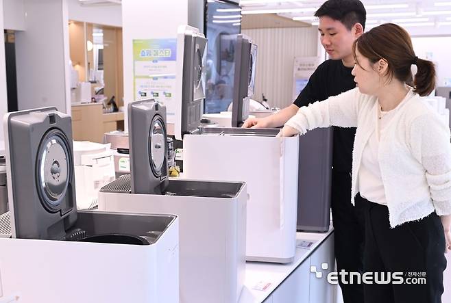 더워지는 날씨에 음식물처리기를 찾는 소비자가 늘고 있다. 서울 송파구 쿠쿠 잠실직영점에서 고객이 미생물을 이용한 제품과 건조분쇄형 음식물처리기를 살펴보고 있다. 박지호기자 jihopress@etnews.com