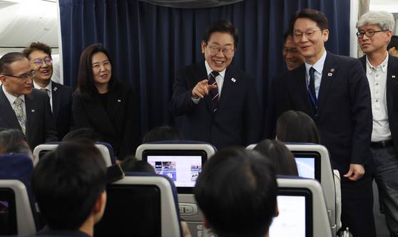 President Lee Jae Myung, center, chats with reporters after the G7 summit in Canada on Air Force One en route to Seoul on June 18. [JOINT PRESS CORPS]