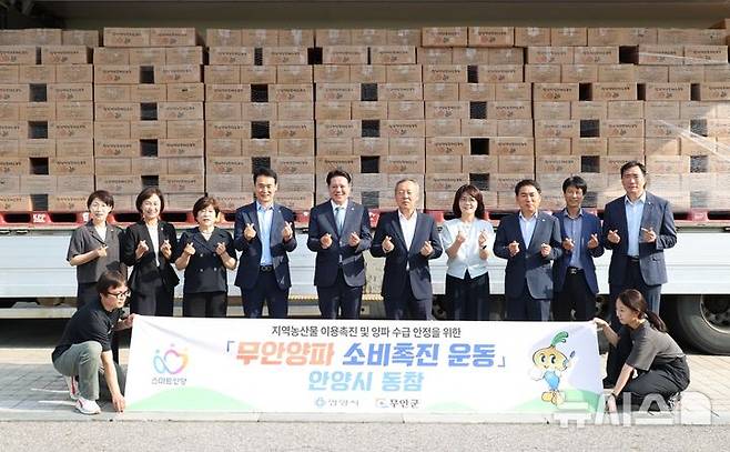 [안양=뉴시스] 최대호 시장(사진 왼쪽 다섯번째) 등 무안산 양파 공동구매 참가자들이 구매한 양파를 배경으로 기념 사진을 촬영하고 있다. (사진=안양시 제공). 2025.06.19.photo@newsis.com