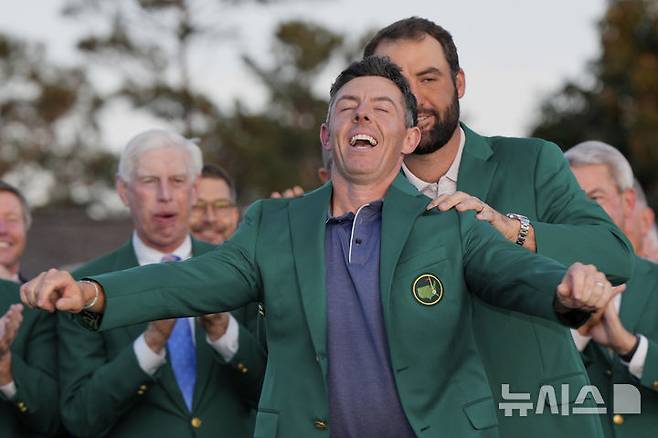 [오거스타=AP/뉴시스] 로리 매킬로이(북아일랜드)가 지난 4월13일(현지 시간) 미 조지아주 오거스타 내셔널 골프클럽에서 열린 제89회 마스터스 토너먼트 정상에 올라 지난해 우승자 스코티 셰플러(미국)가 입혀 주는 '그린 재킷'을 입고 있다. 매킬로이는 최종 합계 11언더파 277타로 저스틴 로즈(영국)와 동타를 이뤄 연장 끝에 우승, 커리어 '그랜드 슬램'을 달성했다. 2025.04.14.