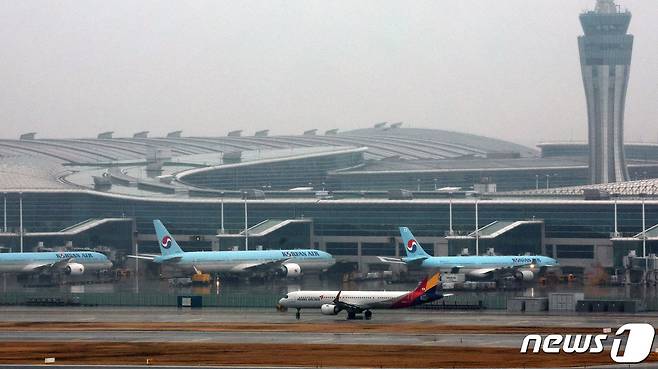 인천국제공항 계류장에 세워진 대한항공 항공기 앞으로 아시아나 항공기가 이륙하고 있다. 2024.1.14/뉴스1 ⓒ News1 장수영 기자