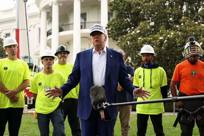 도널드 트럼프 미국 대통령이 18일 워싱턴 DC 백악관 잔디밭에서 깃대 설치 노동자들과 함께 기자회견을 하고 있다. /로이터 연합뉴스