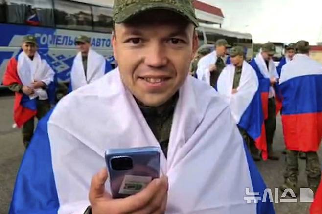 [벨라루스=AP/뉴시스] 19일(현지 시간) 러시아 국방부가 배포한 영상에서 포로 교환을 통해 귀환한 러시아군 병사가 벨라루스의 교환 지점에서 어머니와 통화하고 있다. 주변에는 러시아 국기를 든 병사들이 버스를 기다리고 있다. 2025.06.19. photo@newsis.com