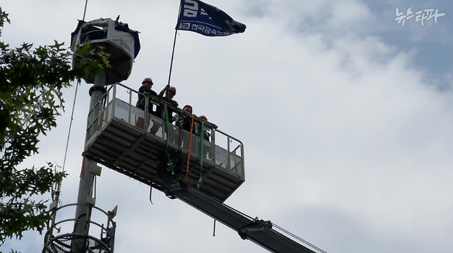 김형수 거제통영고성 조선하청지회 지회장이 고공농성 97일째인 6월 19일 오후 2시경 서울 중구 한화오션 본사 앞에서 고공농성을 중단하고 금속노조 깃발을 흔들며 지상으로 내려 오고 있다