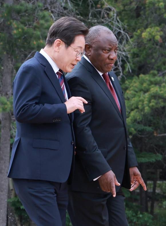 지난 17일(현지시간) 이 대통령과 시릴 라마포사 남아프리카공화국 대통령이 G7 및 초청국 기념촬영을 위해 이동하며 대화하는 모습. 캐내내스키스 연합뉴스