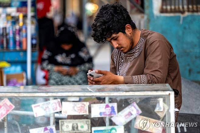 아프간 수도 카불서 휴대전화를 보는 환전상 [AFP 연합뉴스 자료사진. 재판매 및 DB 금지]