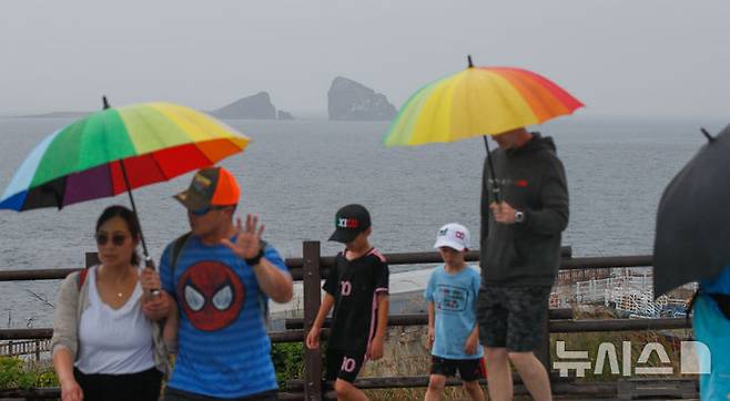 [서귀포=뉴시스] 우장호 기자 = 올해 첫 장맛비가 내리는 12일 오전 제주 서귀포시 대정읍 송악산 둘레길에서 우산을 쓴 관광객들이 걸어가고 있다. 2025.06.12. woo1223@newsis.com