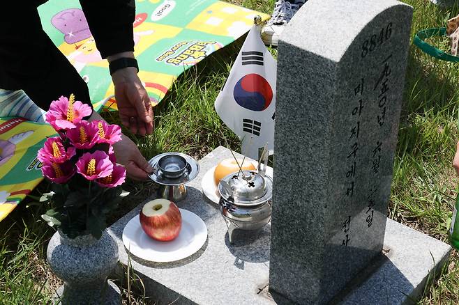 6·25전쟁 75주년을 사흘 앞둔 22일 서울 동작구 국립서울현충원 묘역에서 유족 홍인표씨가 가족들과 함께 아버지 묘지를 찾아 참배하고 있다. 성동훈 기자