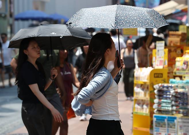 장마를 앞두고 최고 34도 찜통더위가 찾아온 19일 오후 서울 명동거리에서 시민들이 우산으로 더위를 피하고 있다. 2025.6.19 /박성원 기자