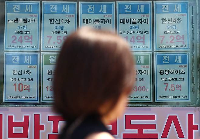 23일 서울 시내의 한 부동산에 붙은 전세 매물 안내문 앞으로 시민이 지나고 있다. /연합뉴스