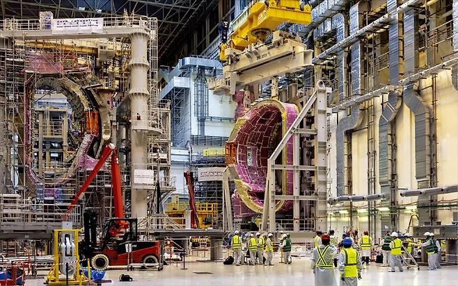 < ‘자석 한 개만 4층 높이’ 국제핵융합실험로 > 최근 공개된 프랑스 남부 카다라슈 국제핵융합실험로(ITER) 건설 현장. ITER 진공용기 일곱 번째 섹터(왼쪽)와 여덟 번째 섹터가 플라스마를 생성·제어하는 대형 초전도 자석과 결합 테스트를 하고 있다.  ITER 제공
