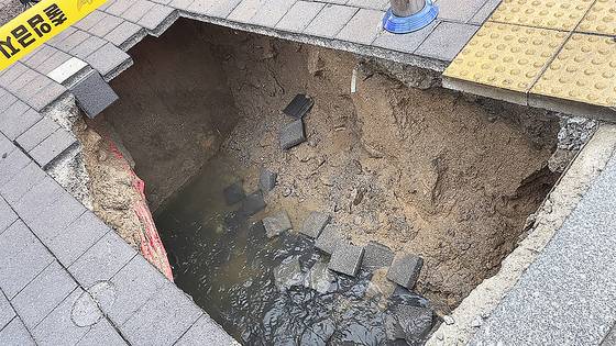A sinkhole lies open on a sidewalk near a crosswalk in Dotong-dong in Namwon, North Jeolla, on June 21. [NORTH JEOLLA FIRE SERVICES]