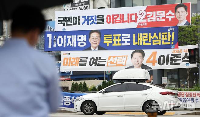 [서울=뉴시스] 김선웅 기자 = 지난 2일 서울 영등포구 한 교차로에서 시민들이 대선 후보 현수막 앞을 지나고 있다. 2025.06.02. mangusta@newsis.com