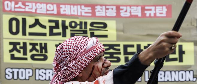 지난해 10월6일 서울 종로구에서 열린 ‘가자지구 학살 1년, 10·6 국제 행동의 날’에 참가한 한 참석자가 팔레스타인 깃발을 흔들며 전쟁 중단 촉구 퍼포먼스를 하고 있다. 연합뉴스