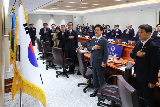 President Lee Jae Myung, center, and ministers salute the flag ahead of a Cabinet meeting at the presidential office in Yongsan District, central Seoul, on June 24. [JOINT PRESS CORPS]