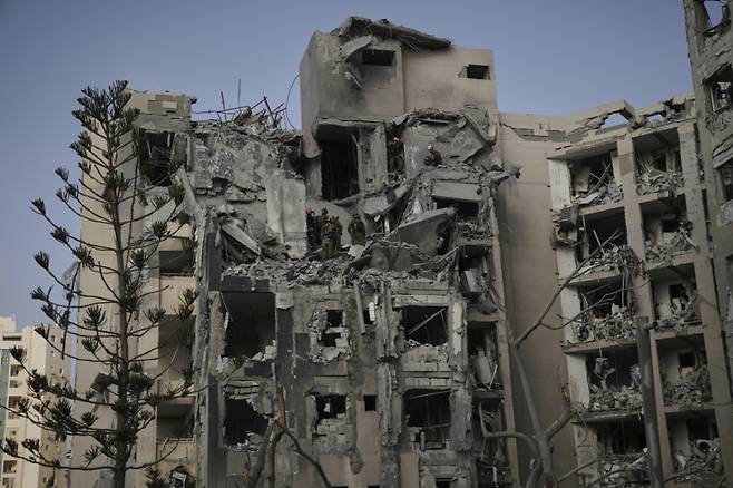 24일(현지 시간) 이스라엘 남부 베르셰바에서 이스라엘 군인과 구조대가 이란의 미사일 공격으로 파괴된 주거 건물 잔해를 수색하고 있다. 도널드 트럼프 미국 대통령이 이란과 이스라엘이 휴전에 합의했다고 발표한 가운데 이란의 미사일 공습으로 이스라엘 남부에서 최소 3명이 숨지고 8명이 다친 것으로 알려졌다. /AP=뉴시스