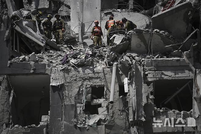 [베르셰바=AP/뉴시스] 24일(현지 시간) 이스라엘 베르셰바에서 이스라엘 군인들이 이란 미사일 공격을 받은 현장을 수습하고 있다. 이스라엘과 미국, 이란이 휴전에 돌입한 지 반나절 만에 이란이 휴전 합의를 어겼다고 이스라엘이 주장했다. 2025.06.24.