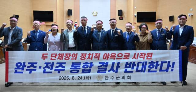 ▲완주군의회 의원들이 24일 본회의장에서 '완주·전주 통합 결사반대'라는 문구가 적힌 현수막을 들고 결의의 뜻을 밝히고 있다. ⓒ완주군의회