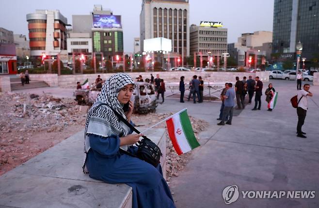 23일(현지시간) 이란 국기 손에 쥔 테헤란 도심의 여성 [테헤란 EPA=연합뉴스. 재판매 및 DB 금지]