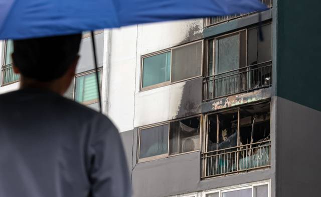 지난 24일 새벽 부산 부산진구 개금동의 한 아파트에서 발생한 화재로 초등학생 자매의 언니가 목숨을 잃은 데 이어 치료를 받던 동생도 숨졌다. 한 주민이 화재 현장을 안타깝게 바라보고 있다. 김종진 기자 kjj1761@