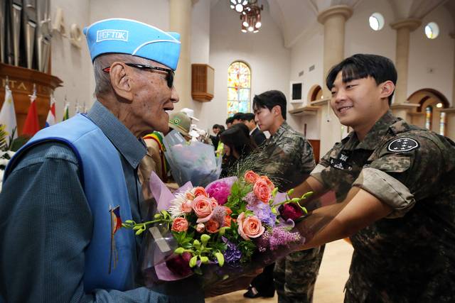필리핀 참전용사 플로렌도 아그불로스 베네딕토 주니어(왼쪽)에게 예비역 학생이 꽃다발을 전달하고 있다.
