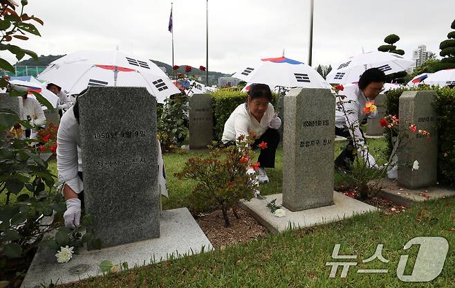 25일 오전 부산 남구 유엔기념공원에서 열린 제75주년 6·25전쟁 참전 유엔전몰용사 추모제에서 태극기 우산을 쓴 참석자들이 유엔군 전몰장병 묘역에 헌화하고 있다. 2025.6.25/뉴스1 ⓒ News1 윤일지 기자