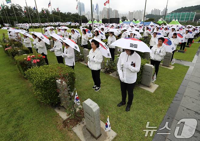 25일 오전 부산 남구 유엔기념공원에서 열린 제75주년 6·25전쟁 참전 유엔전몰용사 추모제에서 태극기 우산을 쓴 참석자들이 유엔군 전몰장병 묘역을 참배하고 있다. 2025.6.25/뉴스1 ⓒ News1 윤일지 기자