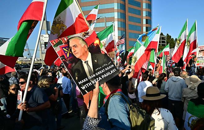 시위대가 23일 미국 로스앤젤레스연방 건물 밖에서 이란 정권 교체를 촉구하고 있다. 이란의 전 국왕이던 모하마드 레자 팔라비의 아들이자 이란 왕위 요구자인 레자 팔라비 포스터를 흔들고 있다. /연합뉴스