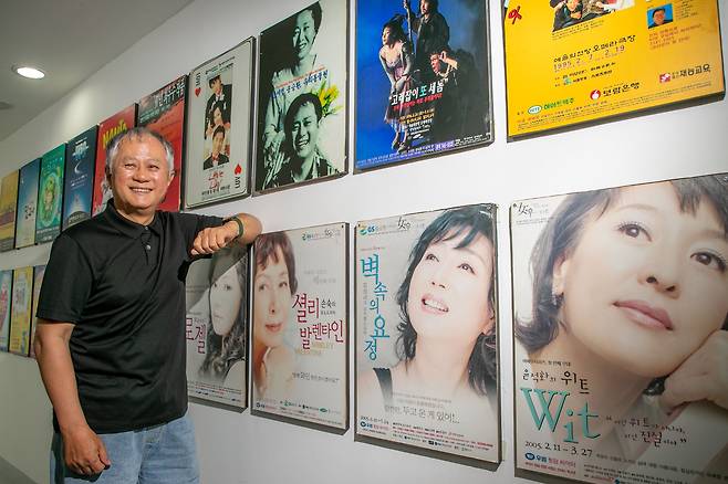 송승환 PMC프러덕션 예술감독이 서울 대학로 사무실 벽에 걸린 공연 액자를 바라보며 웃고 있다. 그가 출연했거나 기획한 작품들이다. 그의 오른쪽 위로 보이는 연극 ‘유리동물원’(1997)은 그와 윤여정의 주연작으로 당시 ‘리얼리즘의 정수를 보여준다’는 찬사를 받았다. /장련성 기자